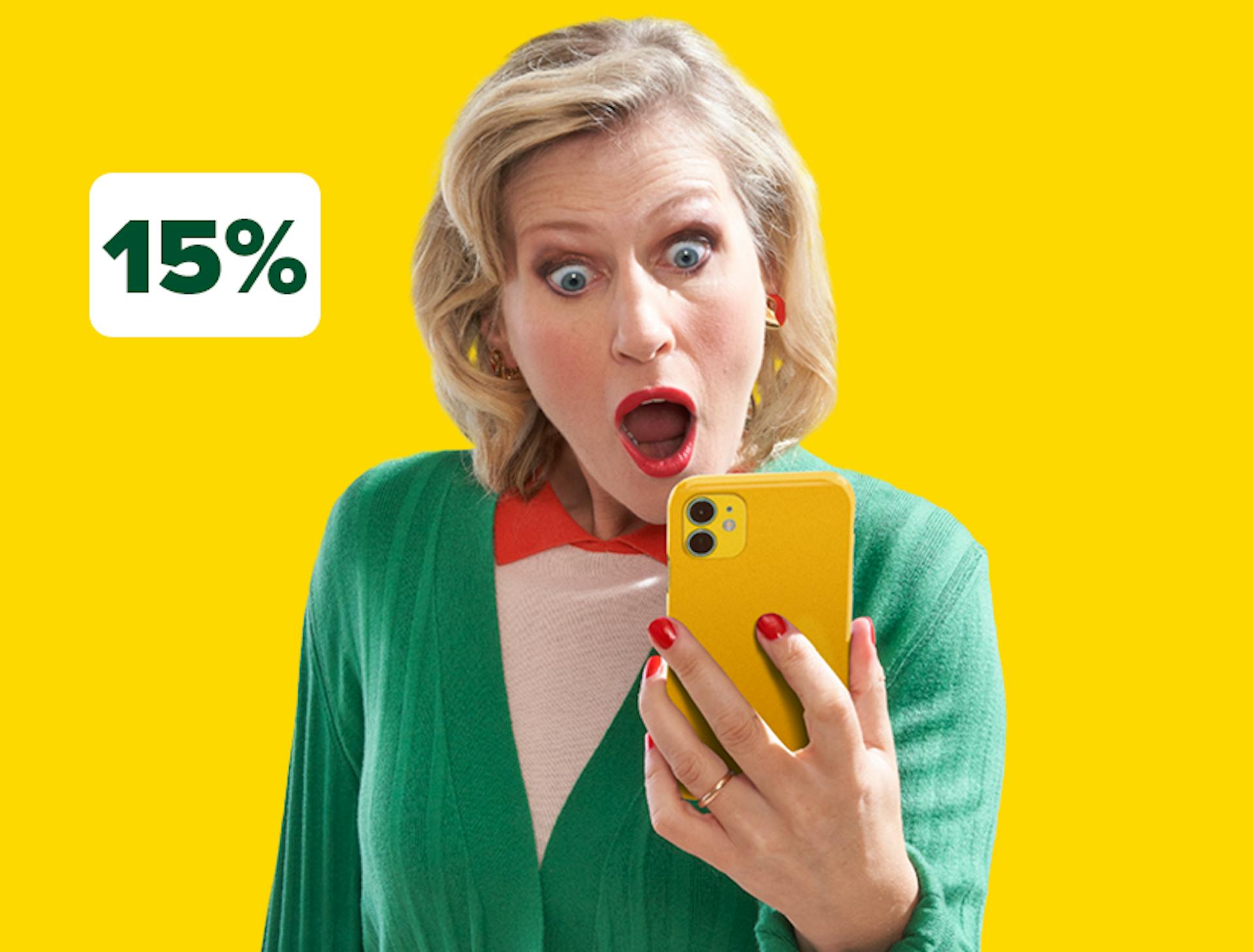Femme souriante en veste verte tenant un smartphone jaune sur un parking et une étiquette de réduction de -15%